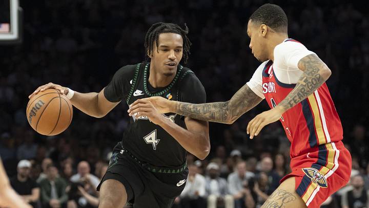 Apr 12, 2026; Minneapolis, Minnesota, USA; Minnesota Timberwolves forward Julian Phillips (4) dribbles against New Orleans Pelicans guard Jordan Hawkins (24) plays defense in the second half at Target Center. 
