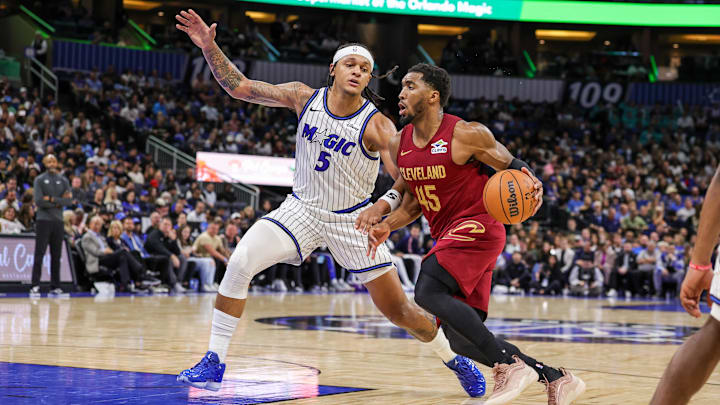 Jan 24, 2026; Orlando, Florida, USA; Cleveland Cavaliers guard Donovan Mitchell (45) drives around Orlando Magic forward Paolo Banchero (5) during the second half at Kia Center. Mandatory Credit: Mike Watters-Imagn Images