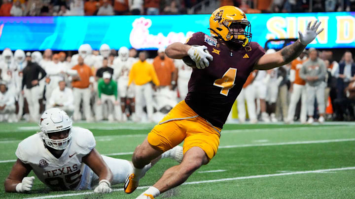 Arizona State running back Cam Skattebo (4) escapes a tackle by Texas defensive lineman Alfred Collins (95) during the fourth quarter in the Chick-fil-A Peach Bowl in Atlanta on Wednesday, Jan. 1, 2025.