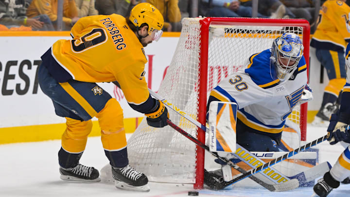Mar 18, 2025; Nashville, Tennessee, USA;  St. Louis Blues goaltender Joel Hofer (30) blocks the shot of Nashville Predators left wing Filip Forsberg (9) during the second period at Bridgestone Arena. Mandatory Credit: Steve Roberts-Imagn Images