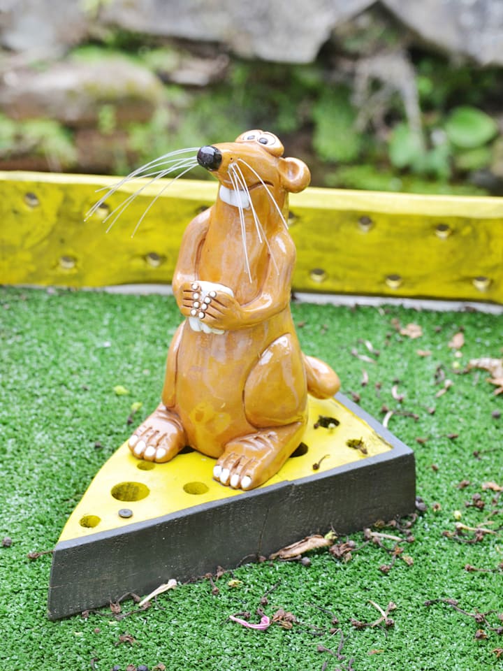 Figure of a mouse holding a tooth on top of a cheese.