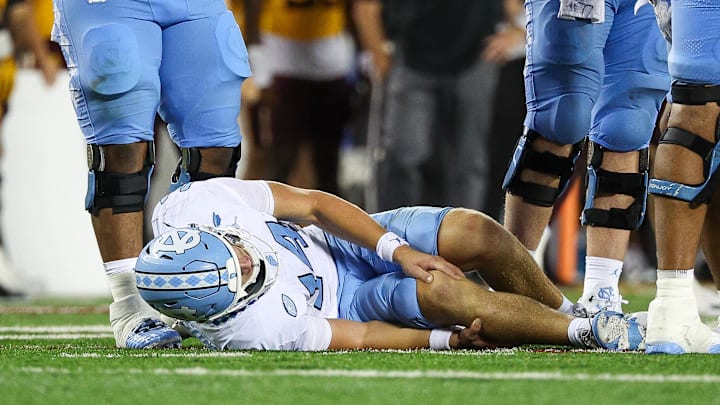Aug 29, 2024; Minneapolis, Minnesota, USA; North Carolina Tar Heels quarterback Max Johnson (14) grabs his knee after being tackled during the second half against the Minnesota Golden Gophers at Huntington Bank Stadium. Mandatory Credit: Matt Krohn-USA TODAY Sports