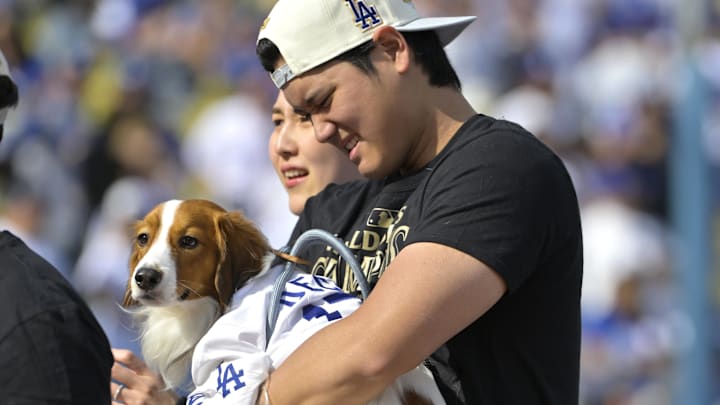 Los Angeles Dodgers designated hitter Shohei Ohtani (17)  holds his dog Decoy, as he walks with off the field his wife Mamiko Tanaka following the teams World Series Championship Celebration.