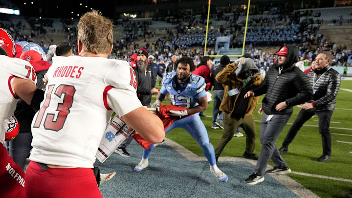 Nov 30, 2024; Chapel Hill, North Carolina, USA; North Carolina Tar Heels players and North Carolina State Wolfpack players fight as State tries to put a Wolfpack flag at midfield after the game at Kenan Memorial Stadium. Mandatory Credit: Bob Donnan-Imagn Images