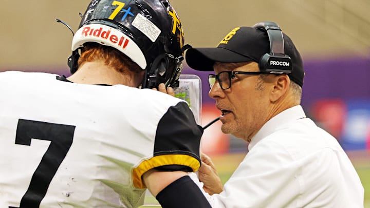 Bishop Garrigan (Algona) sophomore quarterback Tate Foertsch (7) listens to Bishop Garrigan (Algona) Head Coach Marty Wadle as the Bishop Garrigan (Algona) Golden Bears compete against the Bedford Bulldogs for the Eight-Player championship on Thursday, November 16, 2023 at the UNI-Dome in Cedar Falls.