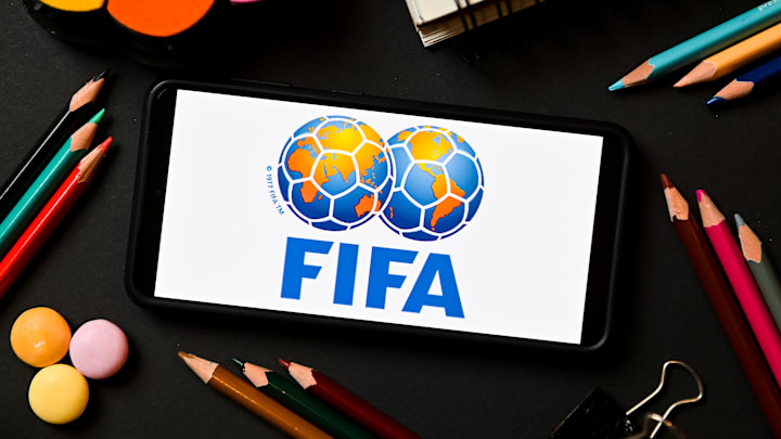 In this photo illustration a FIFA logo seen displayed on a...