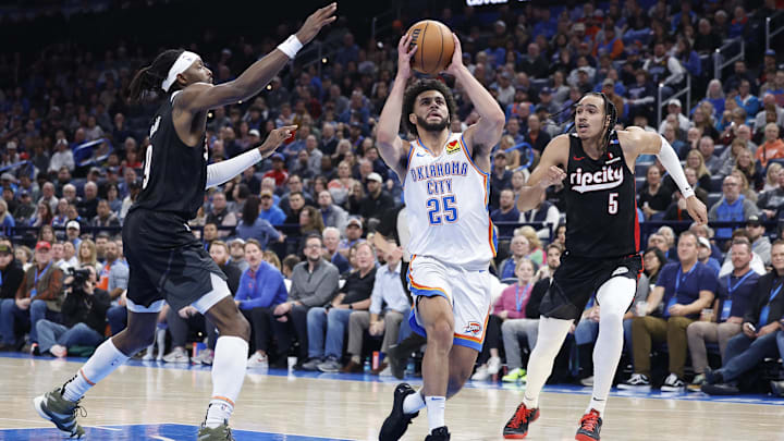 Nov 20, 2024; Oklahoma City, Oklahoma, USA; Oklahoma City Thunder guard Ajay Mitchell (25) drives between Portland Trail Blazers forward Jerami Grant (9) and guard Dalano Banton (5) during the second half at Paycom Center. Mandatory Credit: Alonzo Adams-Imagn Images