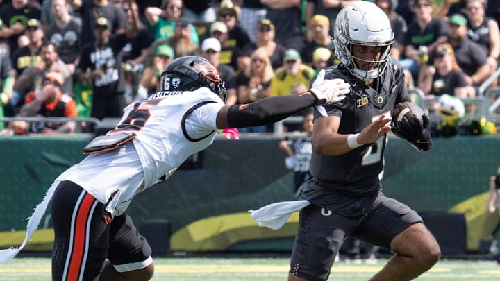 Oregon’s Dante Moore, right, scrambles ahead of Oregon State’s Jaheim Patterson during the second quarter.