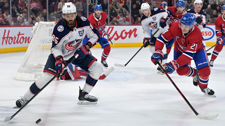 Mar 26, 2026; Montreal, Quebec, CAN; Columbus Blue Jackets forward Kirill Marchenko (86) plays the puck and Montreal Canadiens defenseman Kaiden Guhle (21) defends during the third period at the Bell Centre. Mandatory Credit: Eric Bolte-Imagn Images