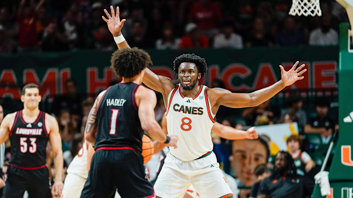 Mar 7, 2026; Coral Gables, Florida, USA; Miami Hurricanes center Ernest Udeh Jr. (8) defends against Louisville Cardinals guard J'vonne Hadley (1) during the second half at Watsco Center. Mandatory Credit: Jeff Romance-Imagn Images