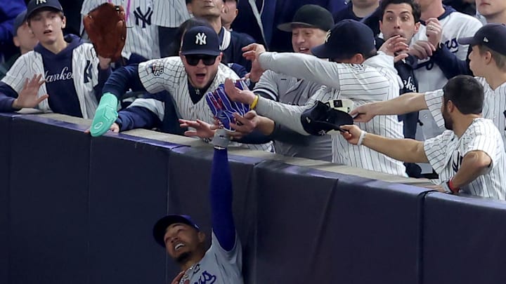 Los Angeles Dodgers outfielder Mookie Betts makes a catch in foul territory as a New York Yankees fan interferes during the first inning in Game 4 of the 2024 MLB World Series at Yankee Stadium.