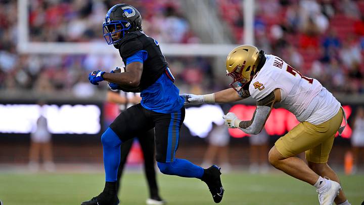 An SMU Mustang running back runs past a Boston College defender. Mandatory Credit: Jerome Miron-Imagn Images
