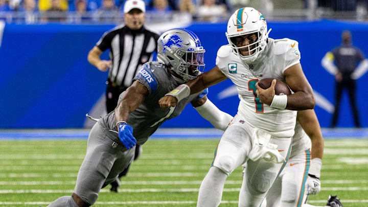 Miami Dolphins quarterback Tua Tagovailoa (1) runs with the ball and tries to avoid a tackle from Detroit Lions cornerback Jeff Okudah (1) during the second half at Ford Field in 2022.