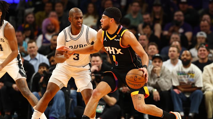 Dec 3, 2024; Phoenix, Arizona, USA; Phoenix Suns guard Devin Booker (1) against San Antonio Spurs guard Chris Paul (3) in the first half of an NBA Cup game at Footprint Center. Mandatory Credit: Mark J. Rebilas-Imagn Images