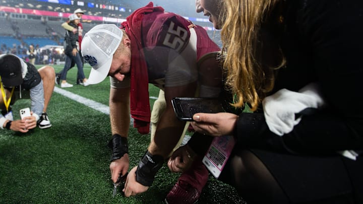 Florida State Seminoles defensive lineman Braden Fiske (55) cuts a piece of the turf after the game. The Florida State Seminoles defeated the Louisville Cardinals 16-6 to claim the ACC Championship title in Charlotte, North Carolina on Saturday, Dec. 2, 2023.