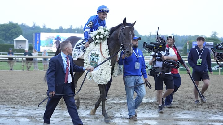 Jun 7, 2025; Saratoga, NY, USA; Junior Alvarado pulls flowers from the championship blanket while up on Sovereignty (2) after winning the Belmont Stakes at Saratoga Race Course. 