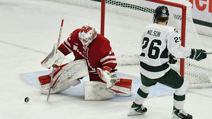 Wisconsin goalie Eli Pulver (30) stops a rolling puck while Michigan State's Eirc Nilson (26) looks on Saturday, Nov. 22, 2025.