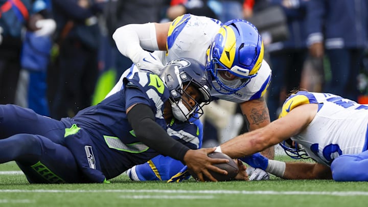 Nov 3, 2024; Seattle, Washington, USA; Seattle Seahawks quarterback Geno Smith (7) recovers a fumble against Los Angeles Rams linebacker Michael Hoecht (97, middle) and linebacker Christian Rozeboom (56, right) during the second quarter at Lumen Field. Mandatory Credit: Joe Nicholson-Imagn Images