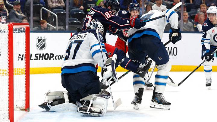 Apr 4, 2026; Columbus, Ohio, USA; Winnipeg Jets goalie Connor Hellebuyck (37) makes a save through the screen of Columbus Blue Jackets right wing Conor Garland (83) during the second period at Nationwide Arena. Mandatory Credit: Russell LaBounty-Imagn Images