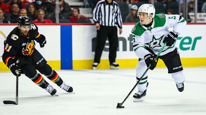 Mar 3, 2026; Calgary, Alberta, CAN; Dallas Stars defenseman Nils Lundkvist (5) controls the puck in front of Calgary Flames center Nazem Kadri (91) during the third period at Scotiabank Saddledome. Mandatory Credit: Sergei Belski-Imagn Images