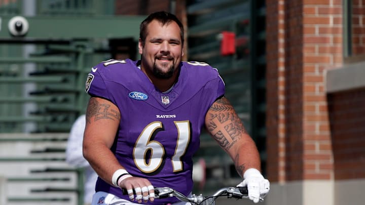 Baltimore Ravens center Nick Samac (61) rides a young fan's bicycle to a joint practice with the Green Bay Packers on Aug. 22, 2024 in Green Bay, Wis.