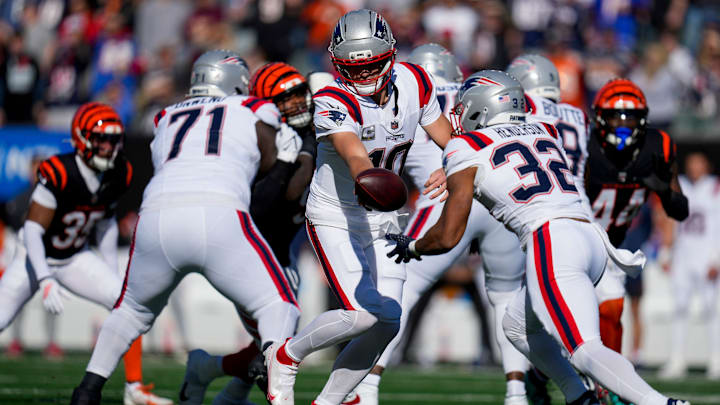 Nov 23, 2025; Cincinnati, Ohio, USA; New England Patriots quarterback Drake Maye (10) hands off to running back TreVeyon Henderson (32) in the first quarter against the Cincinnati Bengals at Paycor Stadium. Mandatory Credit: Sam Greene-USA TODAY Network via Imagn Images