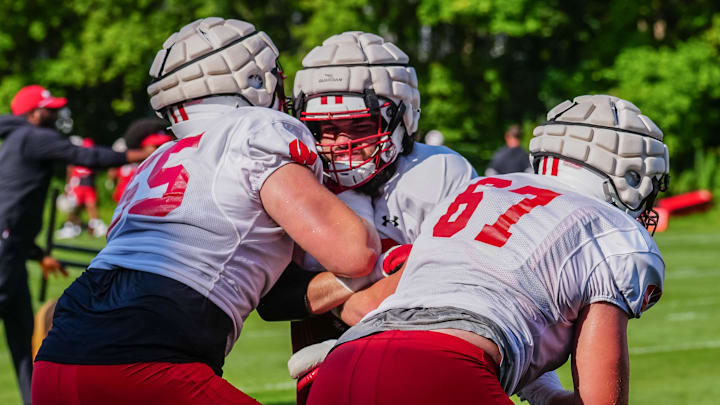 Offensive lineman Joe Brunner, center, takes on Kevin Heywood (55) and JP Benzschawel (67) during football practice Wednesday. 