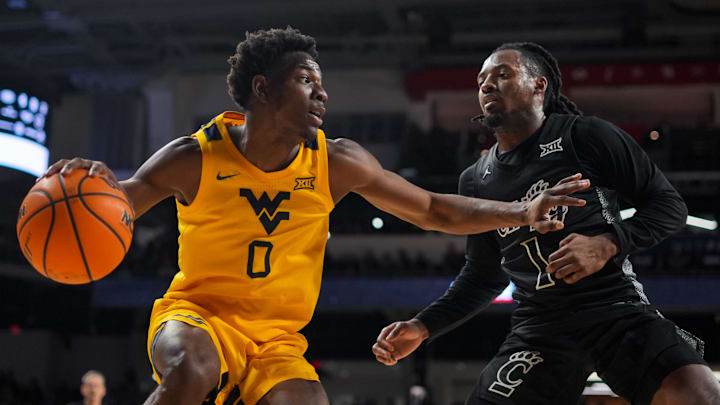 Feb 5, 2026; Cincinnati, Ohio, USA;  West Virginia Mountaineers forward Brenen Lorient (0) dribbles the ball against Cincinnati Bearcats guard Day Day Thomas (1) in the second half at Fifth Third Arena. Mandatory Credit: Aaron Doster-Imagn Images