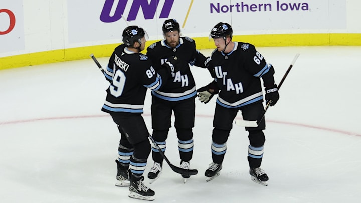 Sep 22, 2024; Des Moines, Iowa, USA;  Utah Hockey Club forward Michael Carcone (53) celebrates with Utah Hockey Club forward Austin Poganski (89)] and Utah Hockey Club forward Ben McCartney (62) after scoring the first goal in franchise history against the St. Louis Blues at Wells Fargo Arena. Mandatory Credit: Reese Strickland-Imagn Images

