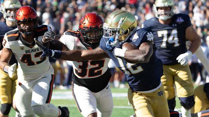 Notre Dame's Jeremiyah Love (12) stiff arms Oregon State players at the 90th Sun Bowl game in El