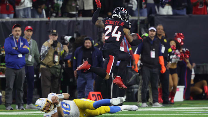Jan 11, 2025; Houston, Texas, USA; Houston Texans cornerback Derek Stingley Jr. (24) leaps over Los Angeles Chargers quarterback Justin Herbert (10) after an interception during the third quarter in an AFC wild card game at NRG Stadium. Mandatory Credit: Troy Taormina-Imagn Images