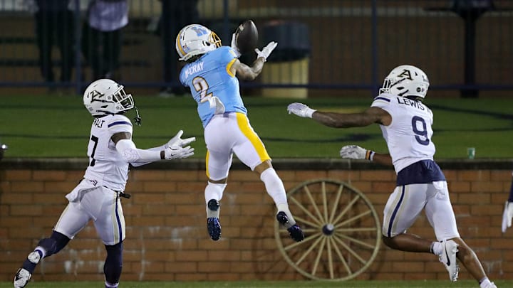 Kent State wide receiver Chrishon McCray catches a second-half touchdown pass between Akron defensive backs Malcom DeWalt IV (left) and Paul Lewis III, Tuesday, Nov. 19, 2024, in Kent.