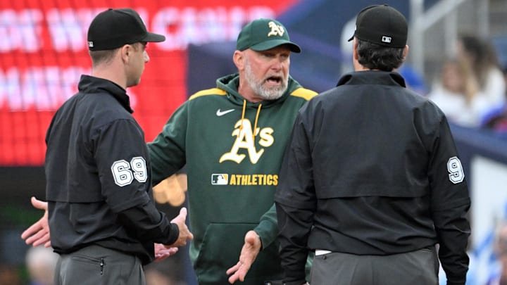 May 30, 2025; Toronto, Ontario, CAN;  Athletics manager Mark Kotsay (7) speaks to umpires Tom Hanahan (69) and James Hoye (92) after a Toronto Blue Jays double play in the second inning at Rogers Centre. Mandatory Credit: Dan Hamilton-Imagn Images