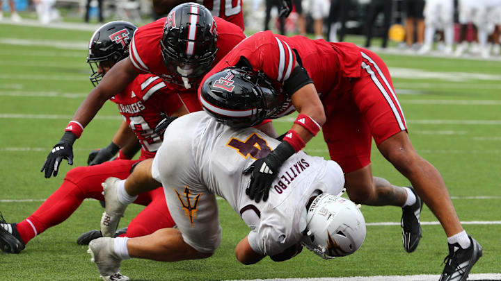 Sep 21, 2024; Lubbock, Texas, USA;  Arizona State Sun Devils running back Cam Skattebo (4) is stopped short of the goal line by Texas Tech Red Raiders defensive back Ben Roberts (13) and defensive safety Chapman Lewis (25) in the second half at Jones AT&T Stadium and Cody Campbell Field. Mandatory Credit: Michael C. Johnson-Imagn Images
