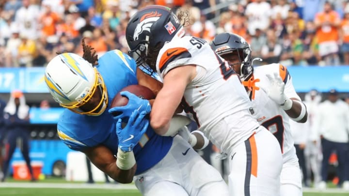 Sep 21, 2025; Inglewood, California, USA; Denver Broncos linebacker Alex Singleton (49) tackles Los Angeles Chargers wide receiver Quentin Johnston (1) during the second half at SoFi Stadium. 