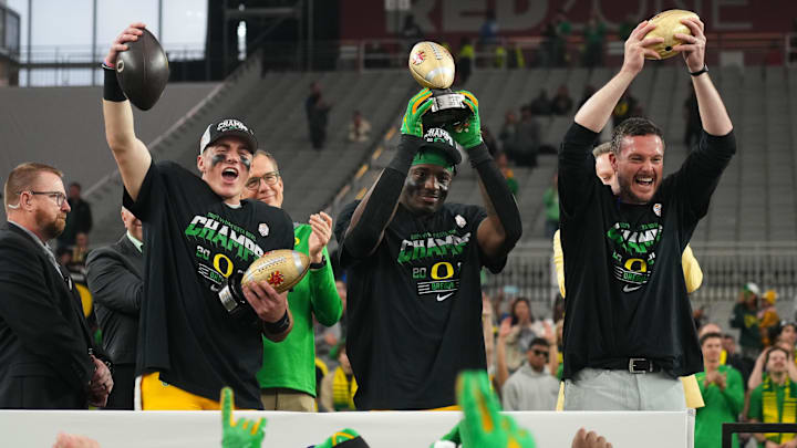 Jan 1, 2024; Glendale, AZ, USA; Oregon Ducks quarterback Bo Nix (10), linebacker Jeffrey Bassa (2) and  head coach Dan Lanning lift the offensive MVP, defensive MVP and championship trophy after a victory in the 2024 Fiesta Bowl against the Liberty Flames at State Farm Stadium. Mandatory Credit: Joe Camporeale-Imagn Images
