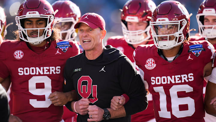 Oklahoma coach Brent Venables locks arms with players before the Armed Forces Bowl.