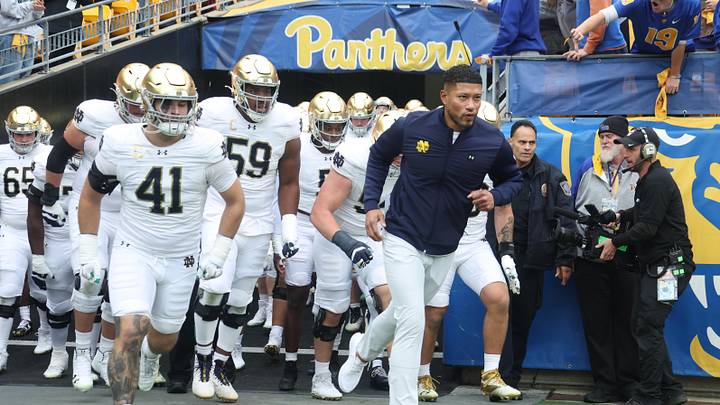 Nov 15, 2025; Pittsburgh, Pennsylvania, USA; Notre Dame Fighting Irish head coach Marcus Freeman (right) leads the team onto the field to play the Pittsburgh Panthers at Acrisure Stadium. Mandatory Credit: Charles LeClaire-Imagn Images Nov 15, 2025; Pittsburgh, Pennsylvania, USA; Notre Dame Fighting Irish head coach Marcus Freeman (right) leads the team onto the field to play the Pittsburgh Panthers at Acrisure Stadium. Mandatory Credit: Charles LeClaire-Imagn Images