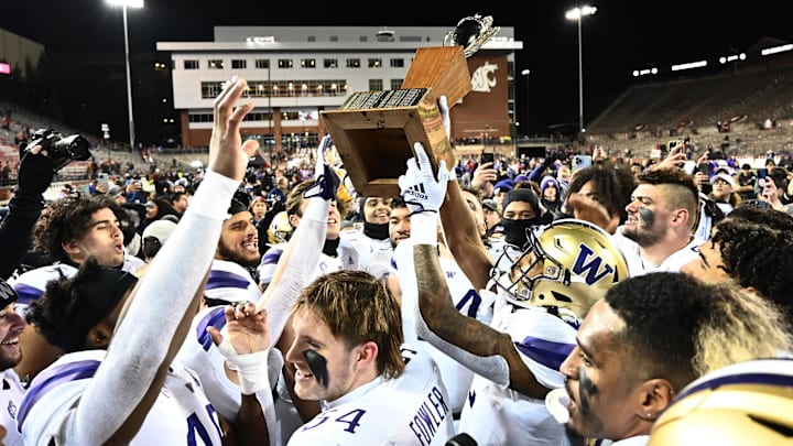 Huskies football players hold up the Apple Cup Trophy after defeating WSU in the 2022 game in Pullman. 