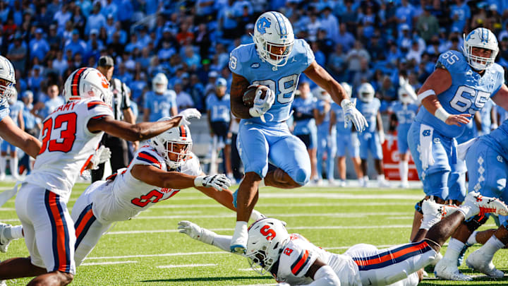 North Carolina Tar Heels running back Omarion Hampton (28) leaps over Syracuse Orange players during the first half of the game at Kenan Memorial Stadium. 