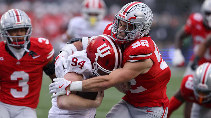 Nov 23, 2024; Columbus, Ohio, USA; Indiana Hoosiers punter James Evans (94) is tackled after recovering his fumble by Ohio State Buckeyes defensive end Caden Curry (92) and cornerback Lorenzo Styles Jr. (3) during the second quarter at Ohio Stadium. 