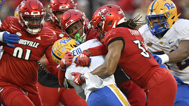 Nov 23, 2024; Louisville, Kentucky, USA; Louisville Cardinals linebacker Stanquan Clark (6) and linebacker TJ Quinn (34) tackle Pittsburgh Panthers running back Desmond Reid (0) during the first half at L&N Federal Credit Union Stadium. Mandatory Credit: Jamie Rhodes-Imagn Images Nov 23, 2024; Louisville, Kentucky, USA; Louisville Cardinals linebacker Stanquan Clark (6) and linebacker TJ Quinn (34) tackle Pittsburgh Panthers running back Desmond Reid (0) during the first half at L&N Federal Credit Union Stadium. Mandatory Credit: Jamie Rhodes-Imagn Images