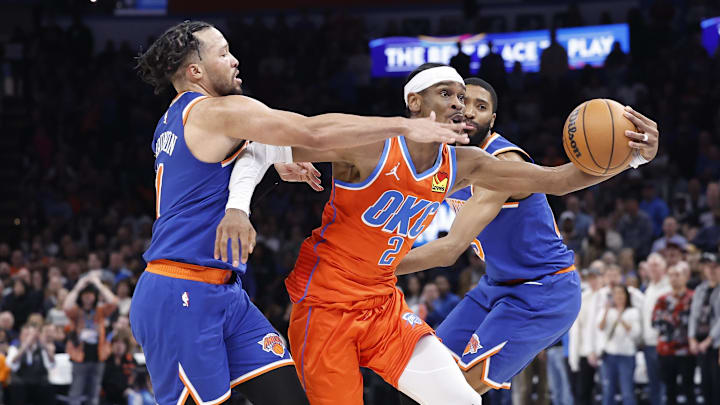 Jan 3, 2025; Oklahoma City, Oklahoma, USA; Oklahoma City Thunder guard Shai Gilgeous-Alexander (2) drives between New York Knicks guard Jalen Brunson (11) and forward Mikal Bridges (25) during the second half at Paycom Center. Mandatory Credit: Alonzo Adams-Imagn Images