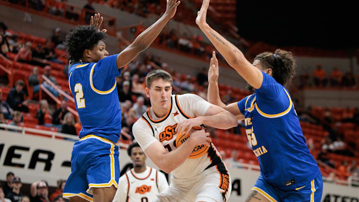 Feb 24, 2026; Stillwater, Oklahoma, USA; Oklahoma State Cowboys forward Andrija Vukovic (19) protects the ball between West Virginia Mountaineers guard Amir Jenkins (2) and West Virginia Mountaineers center Harlan Obioha (55) during the first half at Gallagher-Iba Arena. Mandatory Credit: William Purnell-Imagn Images