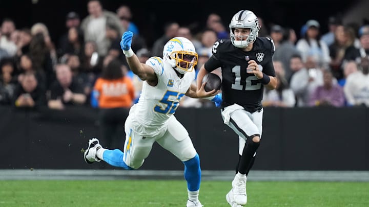 Jan 5, 2025; Paradise, Nevada, USA; Las Vegas Raiders quarterback Aidan O'Connell (12) carries the ball against Los Angeles Chargers linebacker Khalil Mack (52) in the second half at Allegiant Stadium. Mandatory Credit: Kirby Lee-Imagn Images