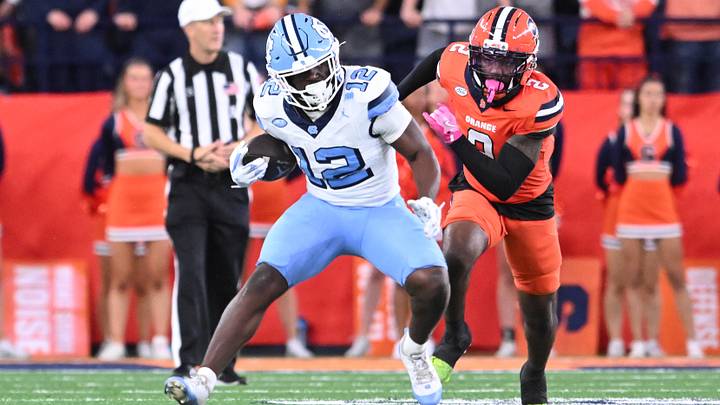 Oct 31, 2025; Syracuse, New York, USA; North Carolina Tar Heels running back Demon June (12) runs past Syracuse Orange cornerback Duce Chestnut (2) in the third quarter at the JMA Wireless Dome. Mandatory Credit: Mark Konezny-Imagn Images