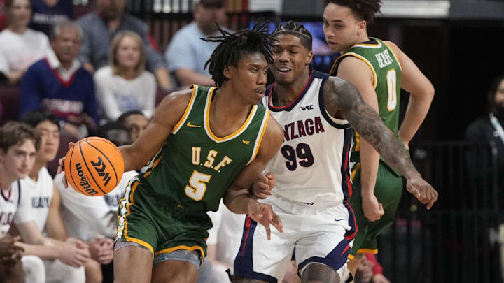 March 10, 2025; Las Vegas, NV, USA; San Francisco Dons guard Tyrone Riley IV (5) dribbles the basketball against Gonzaga Bulldogs guard Khalif Battle (99) during the first half in the semifinal of the West Coast Conference tournament at Orleans Arena. Mandatory Credit: Kyle Terada-Imagn Images