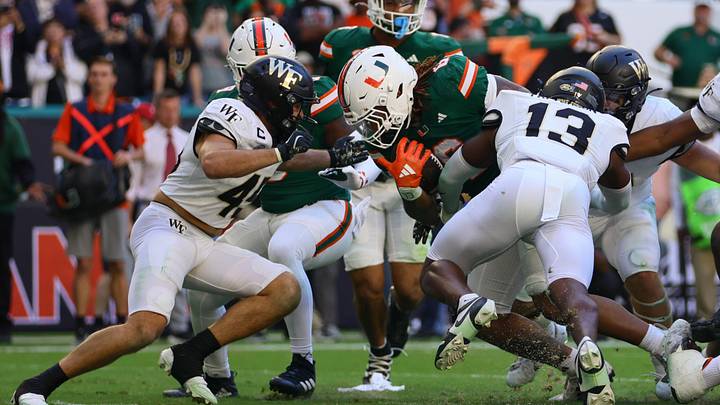 Nov 23, 2024; Miami Gardens, Florida, USA; Miami Hurricanes running back Damien Martinez (6) runs with the football as Wake Forest Demon Deacons defensive back Davaughn Patterson (13) attempts a tackle during the fourth quarter at Hard Rock Stadium. Mandatory Credit: Sam Navarro-Imagn Images Nov 23, 2024; Miami Gardens, Florida, USA; Miami Hurricanes running back Damien Martinez (6) runs with the football as Wake Forest Demon Deacons defensive back Davaughn Patterson (13) attempts a tackle during the fourth quarter at Hard Rock Stadium. Mandatory Credit: Sam Navarro-Imagn Images