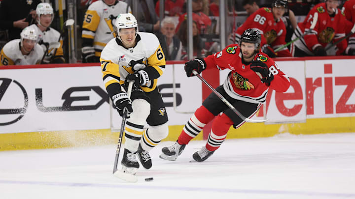 Apr 6, 2025; Chicago, Illinois, USA; Pittsburgh Penguins right wing Rickard Rakell (67) and Chicago Blackhawks left wing Landon Slaggert (84) battle for control of the puck during the first period at United Center. Mandatory Credit: Talia Sprague-Imagn Images