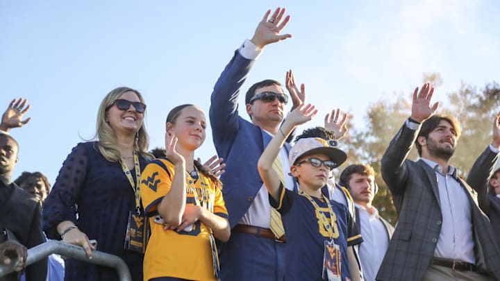 Oct 19, 2024; Morgantown, West Virginia, USA; West Virginia Mountaineers head coach Neal Brown and his family waives to children at the WVU Medicine Children’s Hospital as they arrive for a game against the Kansas State Wildcats at Mountaineer Field at Milan Puskar Stadium. Mandatory Credit: Ben Queen-Imagn Images